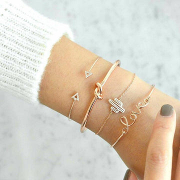 Four stacked charm bracelets featuring love, knot, cactus, and arrow charms